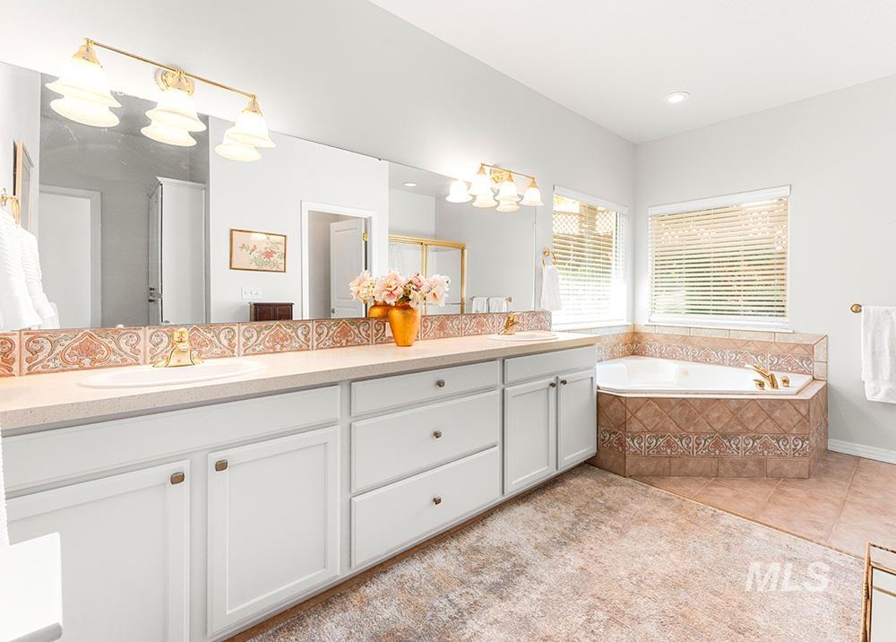 Full bathroom with double vanity, tile patterned floors, and a garden tub
