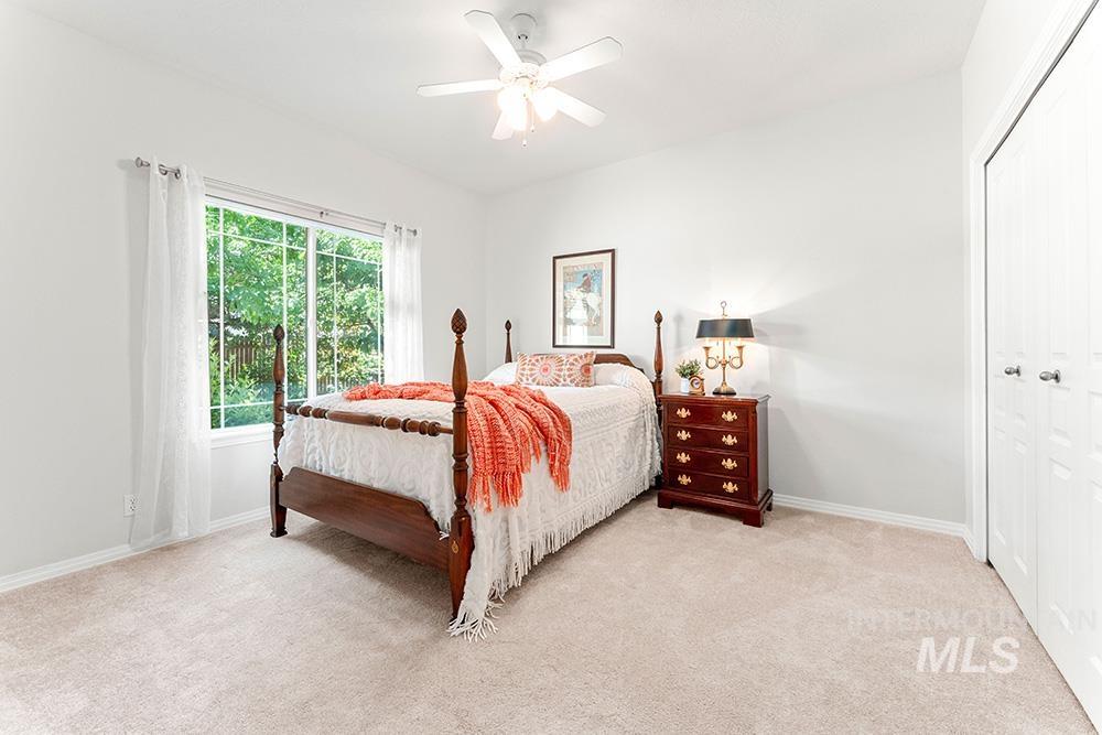 Carpeted bedroom featuring ceiling fan and a closet