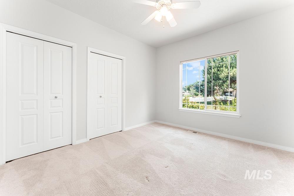 Unfurnished bedroom with carpet, two closets, and a ceiling fan
