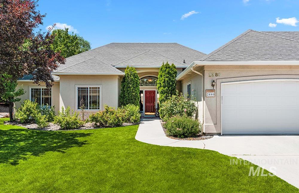 View of front facade featuring stucco siding, a front lawn, driveway, and an attached garage