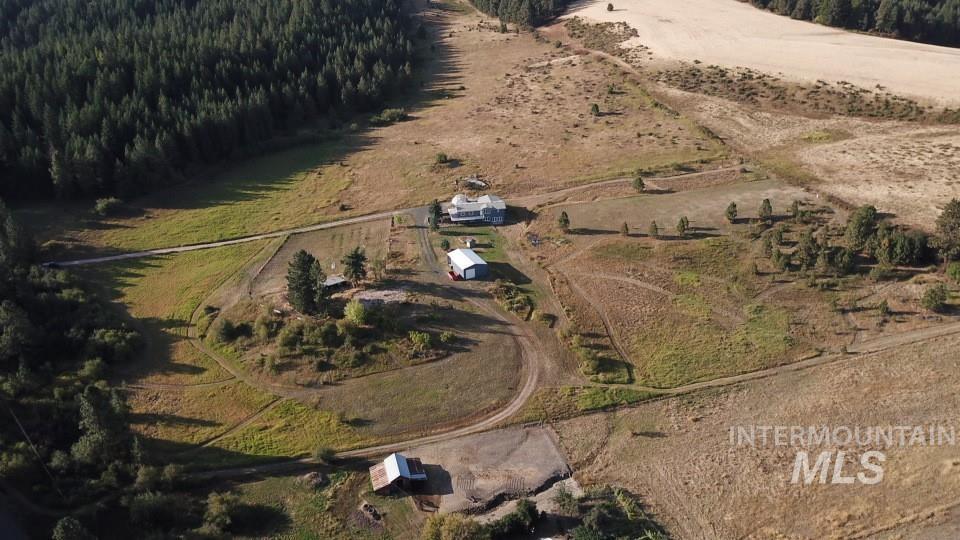 Aerial view of property and surrounding area featuring rural landscape and a forest
