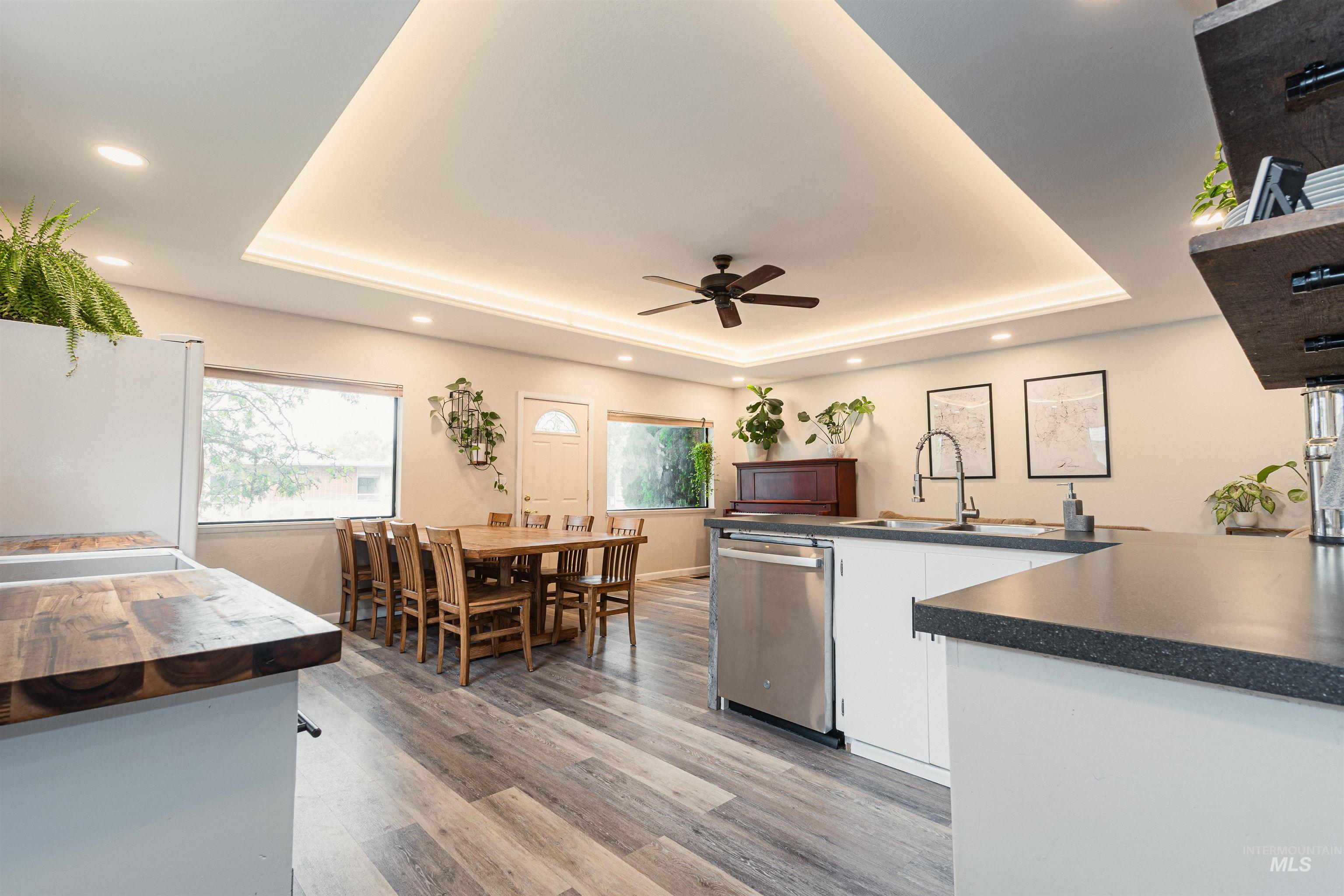 Living room with a ceiling fan, recessed lighting, a tray ceiling, and light wood finished floors