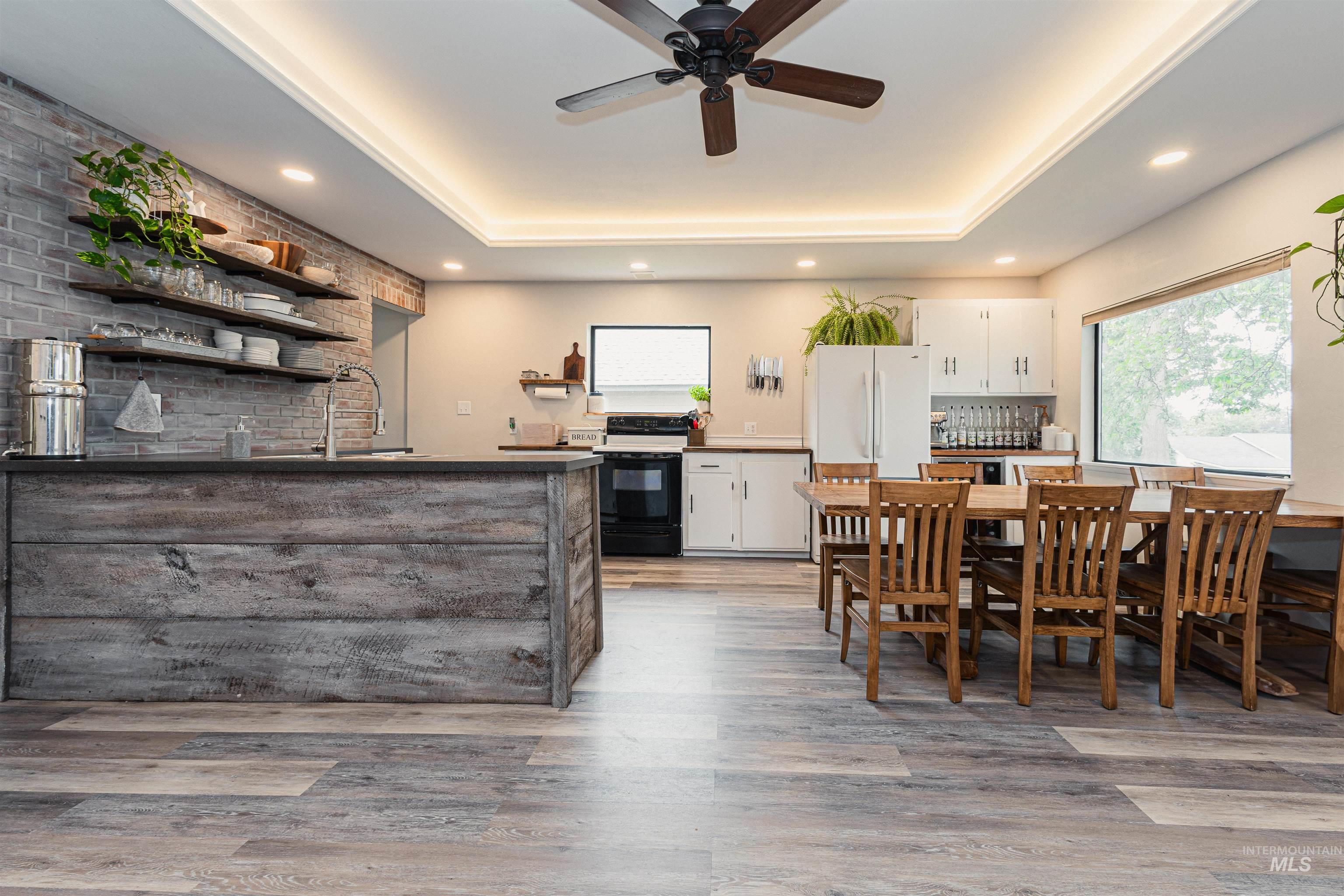 Kitchen featuring white cabinets, open shelves, open floor plan, a peninsula, and light wood finished floors