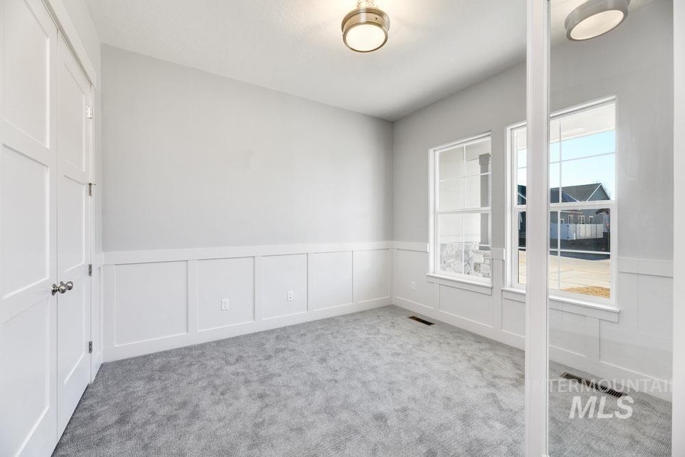 Carpeted spare room with a decorative wall and wainscoting