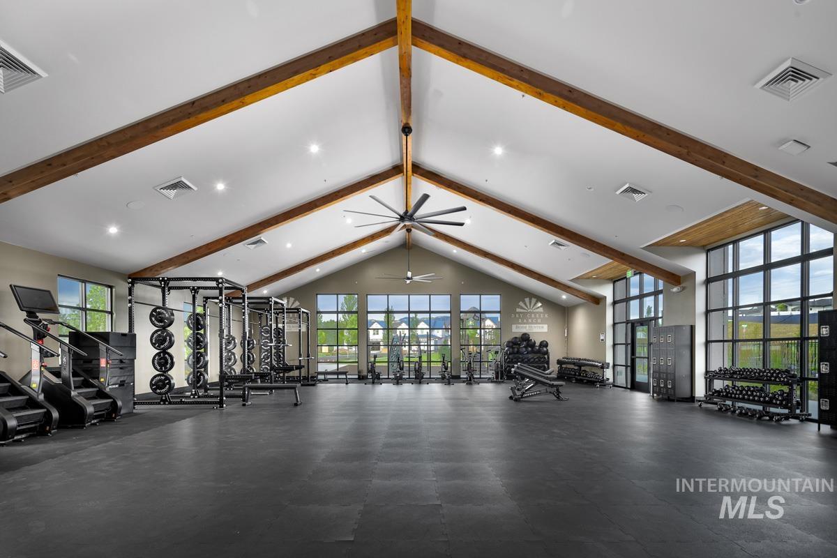 Workout area featuring plenty of natural light, beamed ceiling, ceiling fan, and high vaulted ceiling
