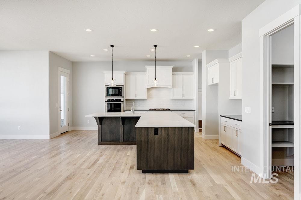 Kitchen with a center island with sink, white cabinets, a breakfast bar area, decorative backsplash, and recessed lighting