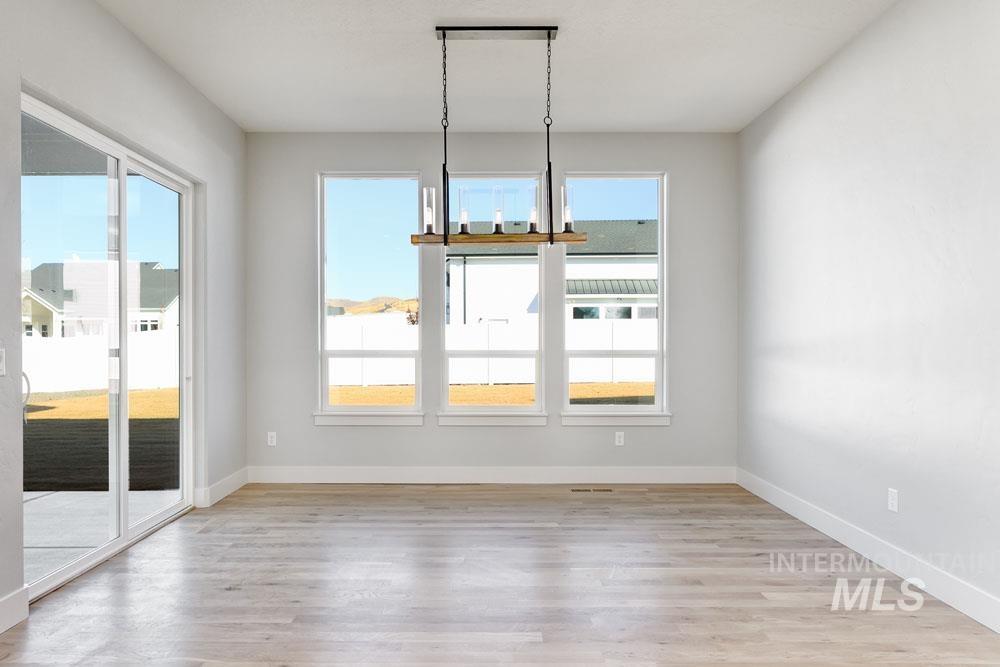 Unfurnished dining area featuring a chandelier and light wood finished floors