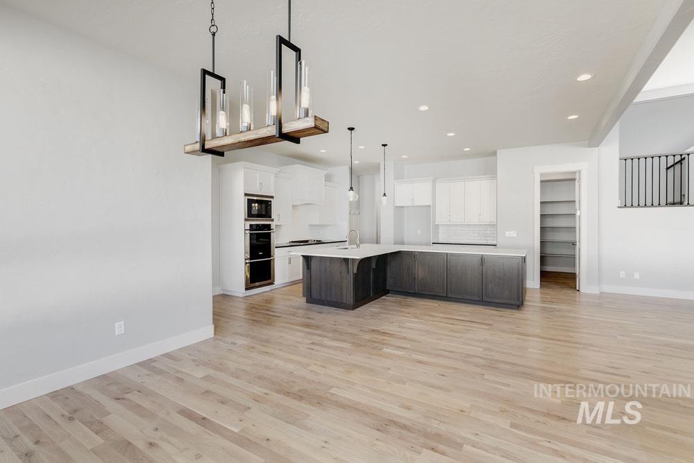 Kitchen with open floor plan, white cabinetry, a large island, and recessed lighting
