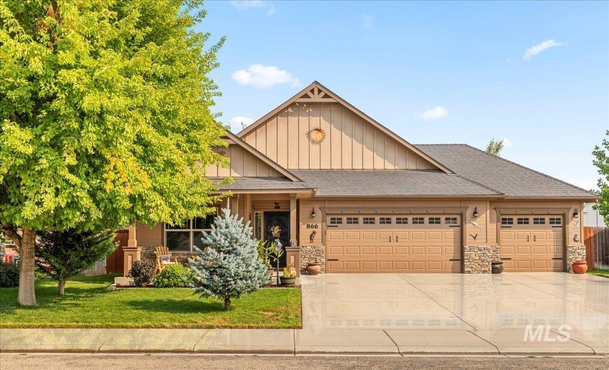 Craftsman-style home with board and batten siding, stone siding, a shingled roof, and a garage