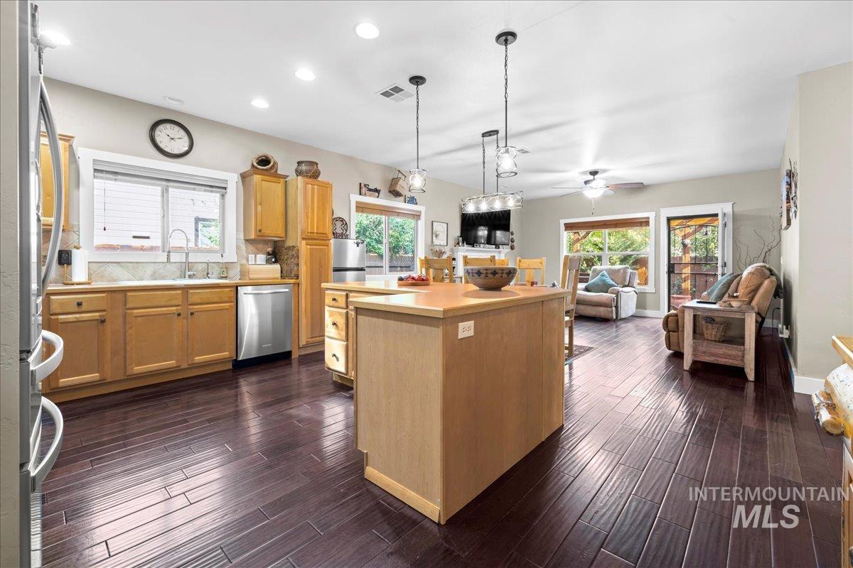 Kitchen featuring light countertops, pendant lighting, open floor plan, a kitchen island, and appliances with stainless steel finishes