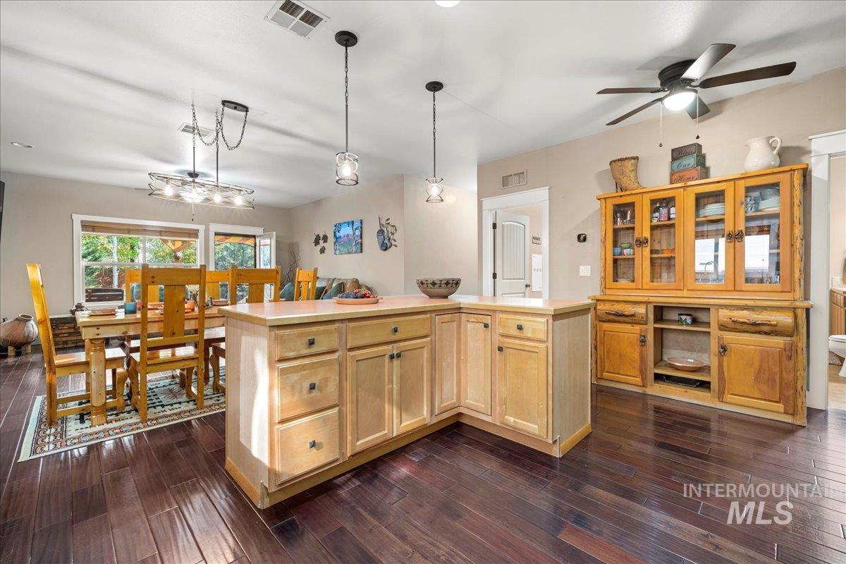Kitchen featuring light countertops, a center island, pendant lighting, dark wood-style floors, and open floor plan