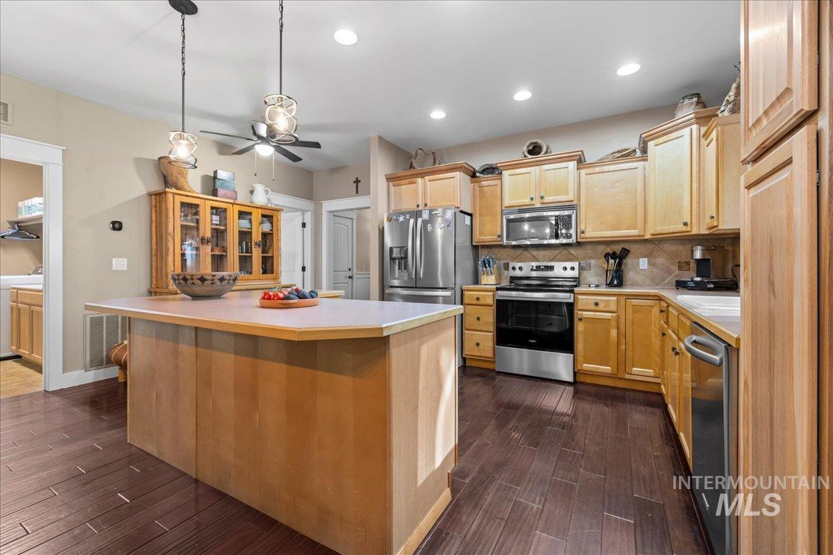 Kitchen featuring backsplash, light countertops, appliances with stainless steel finishes, decorative light fixtures, and recessed lighting