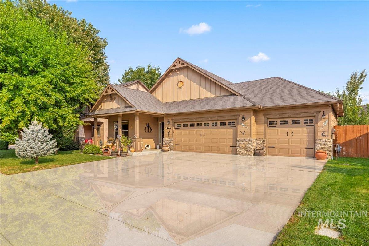 Craftsman-style home with an attached garage, board and batten siding, driveway, covered porch, and stone siding