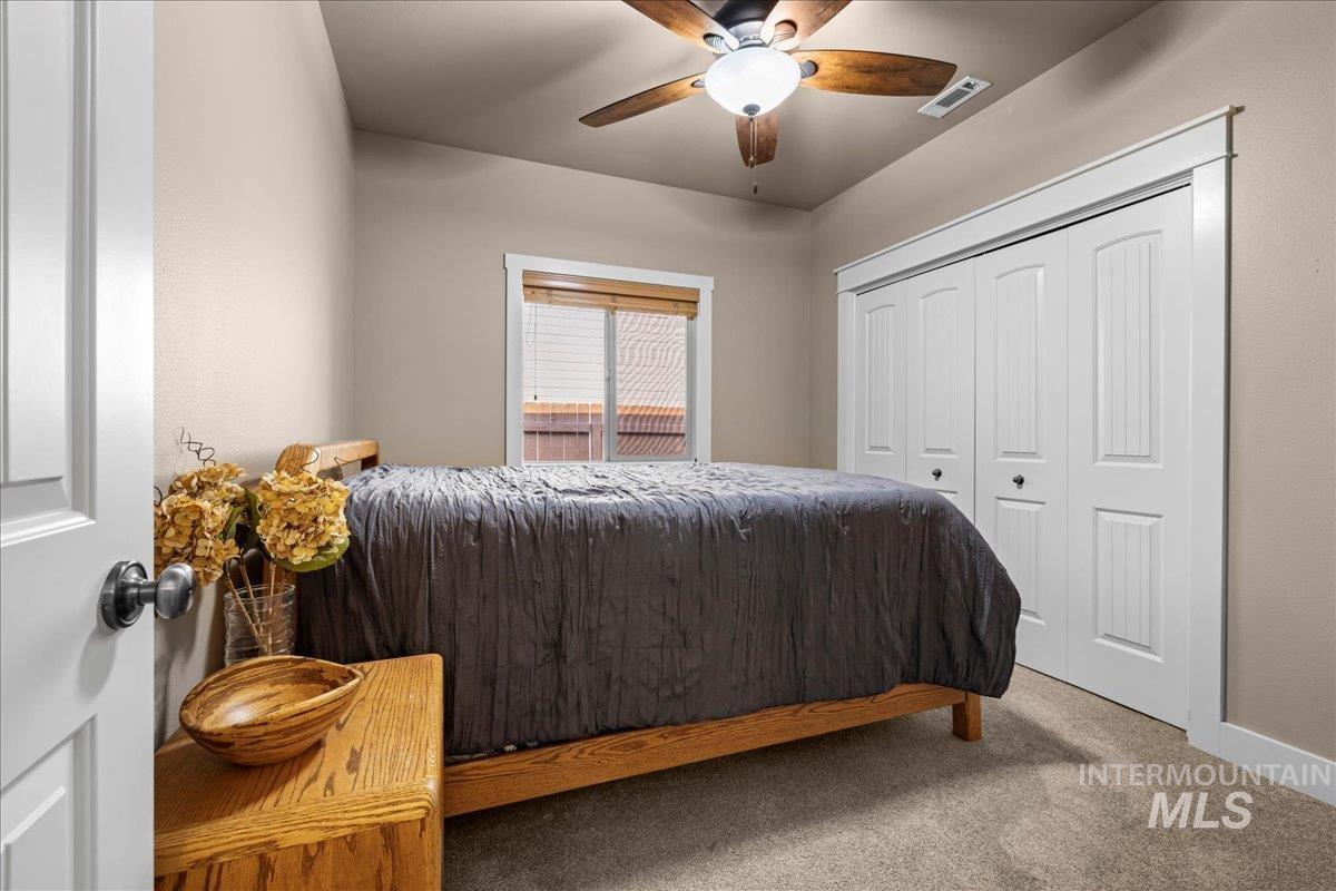Carpeted bedroom featuring ceiling fan and a closet
