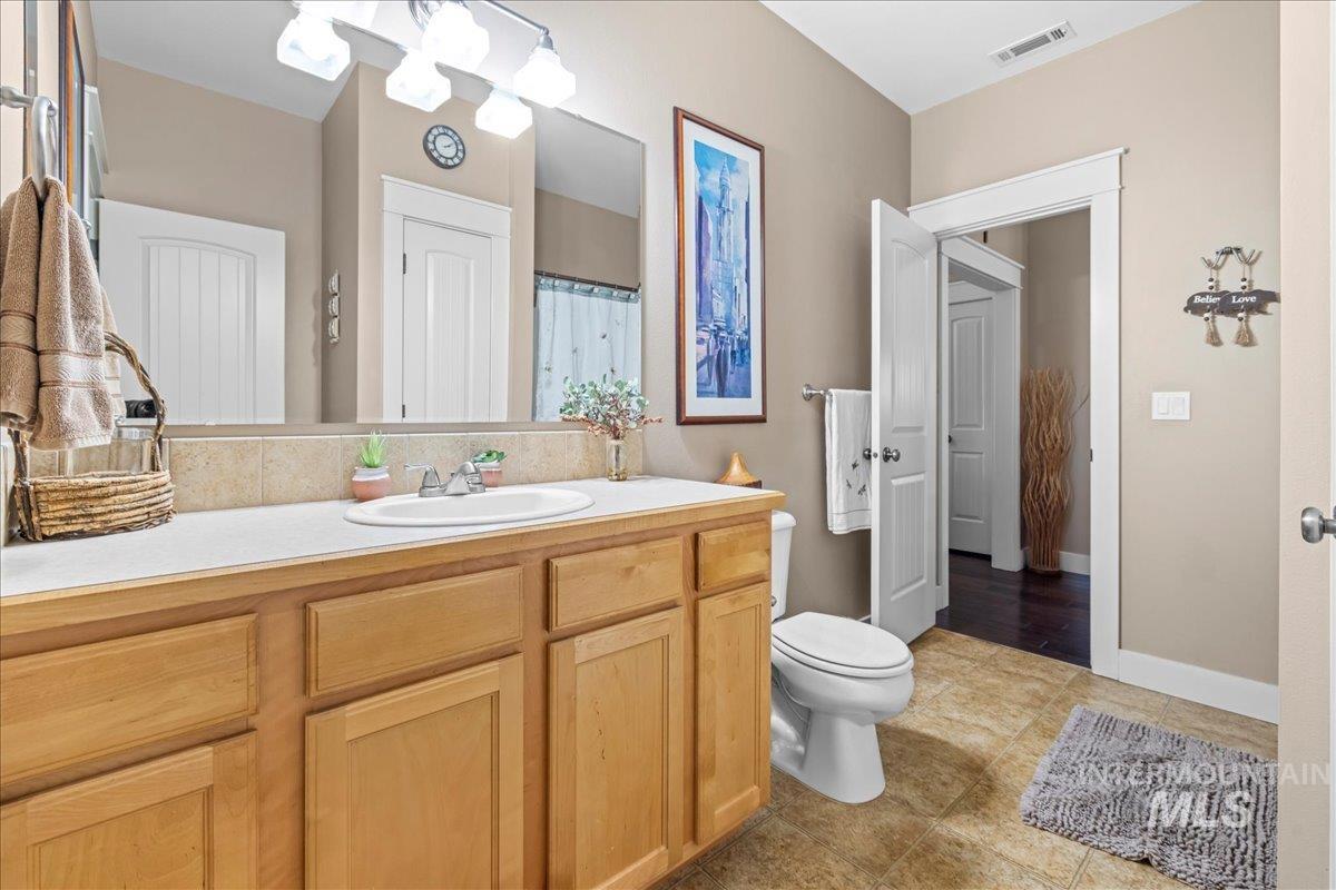 Full bathroom with vanity, light tile patterned floors, and curtained shower