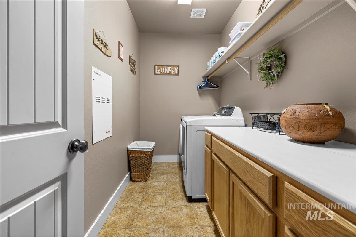 Laundry area with washer and dryer, light tile patterned flooring, and cabinet space