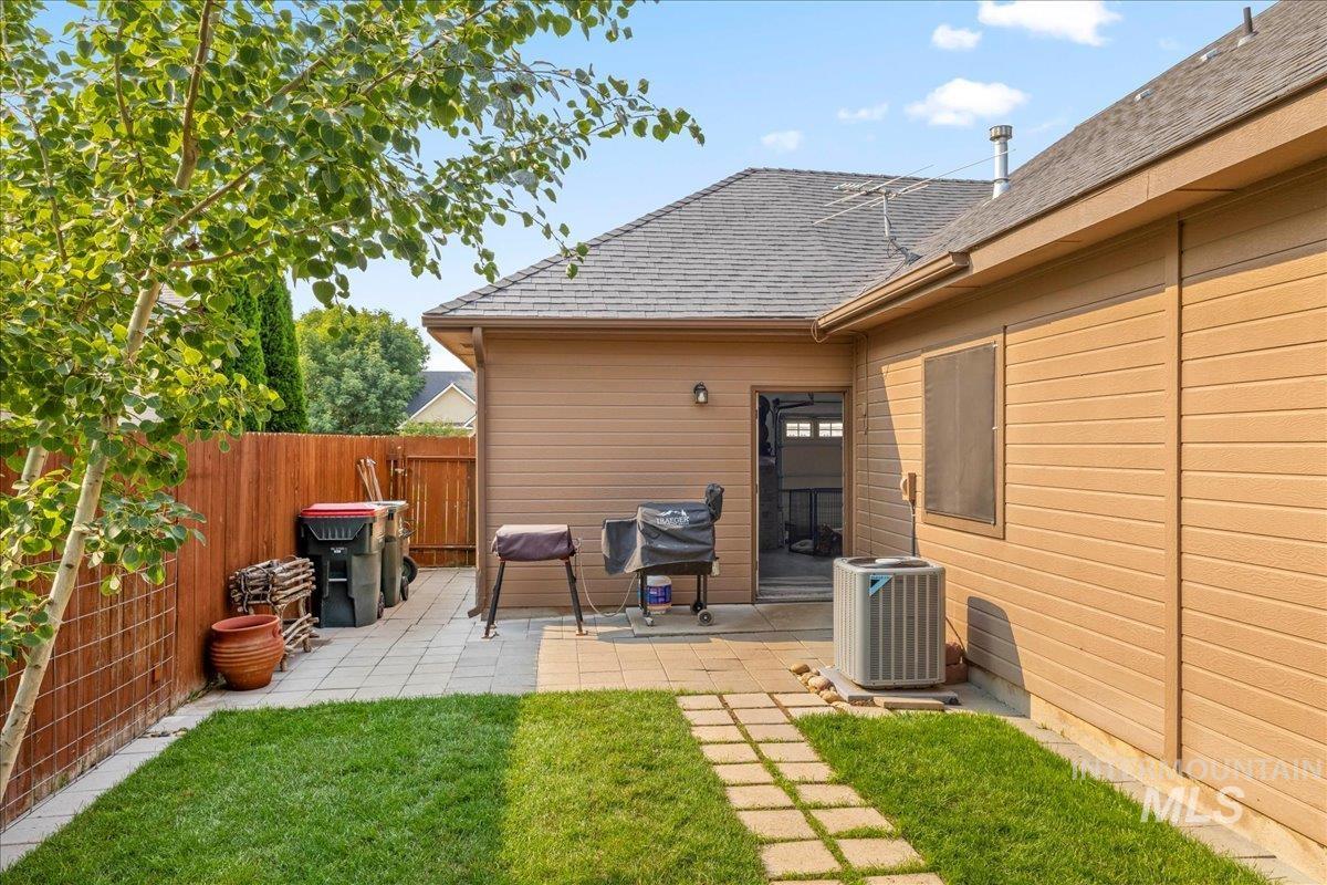 Rear view of house featuring a fenced backyard, roof with shingles, and a patio area