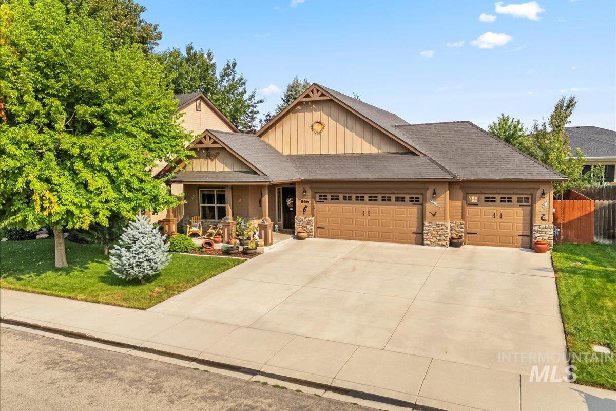 Craftsman-style house featuring board and batten siding, a garage, a shingled roof, covered porch, and driveway