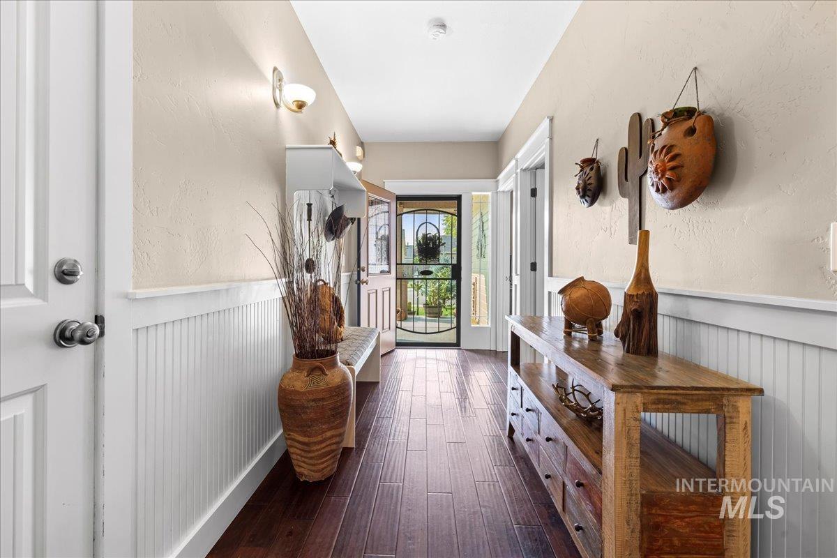 Corridor featuring a wainscoted wall, dark wood finished floors, and a textured wall