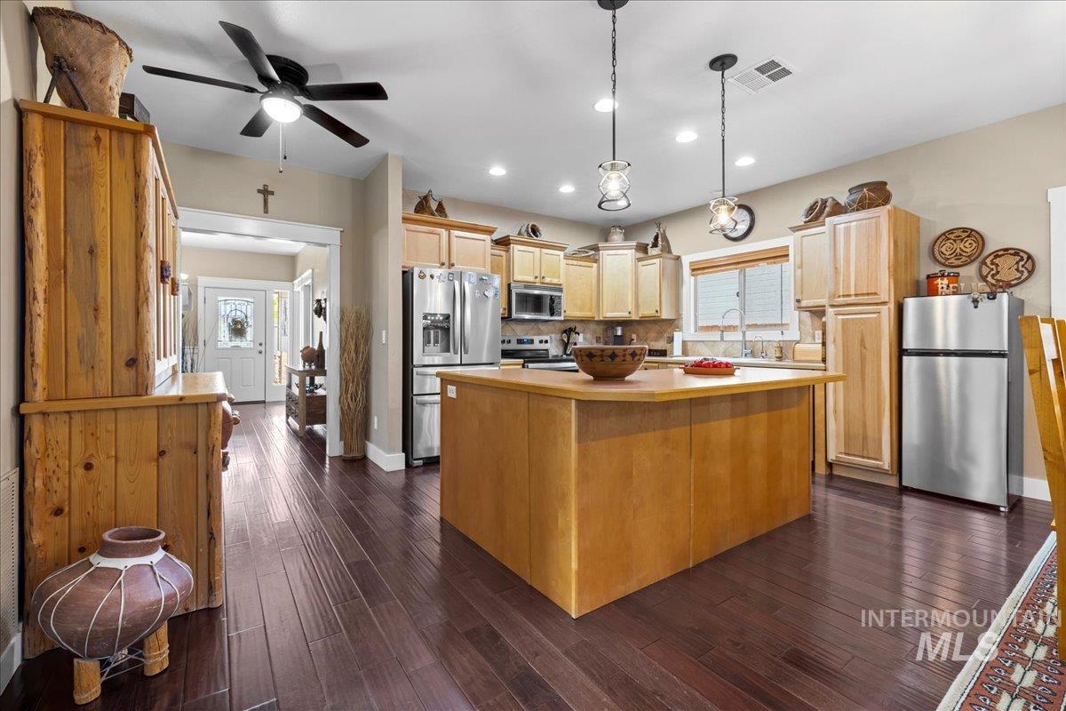 Kitchen with stainless steel appliances, light countertops, decorative light fixtures, recessed lighting, and dark wood-type flooring