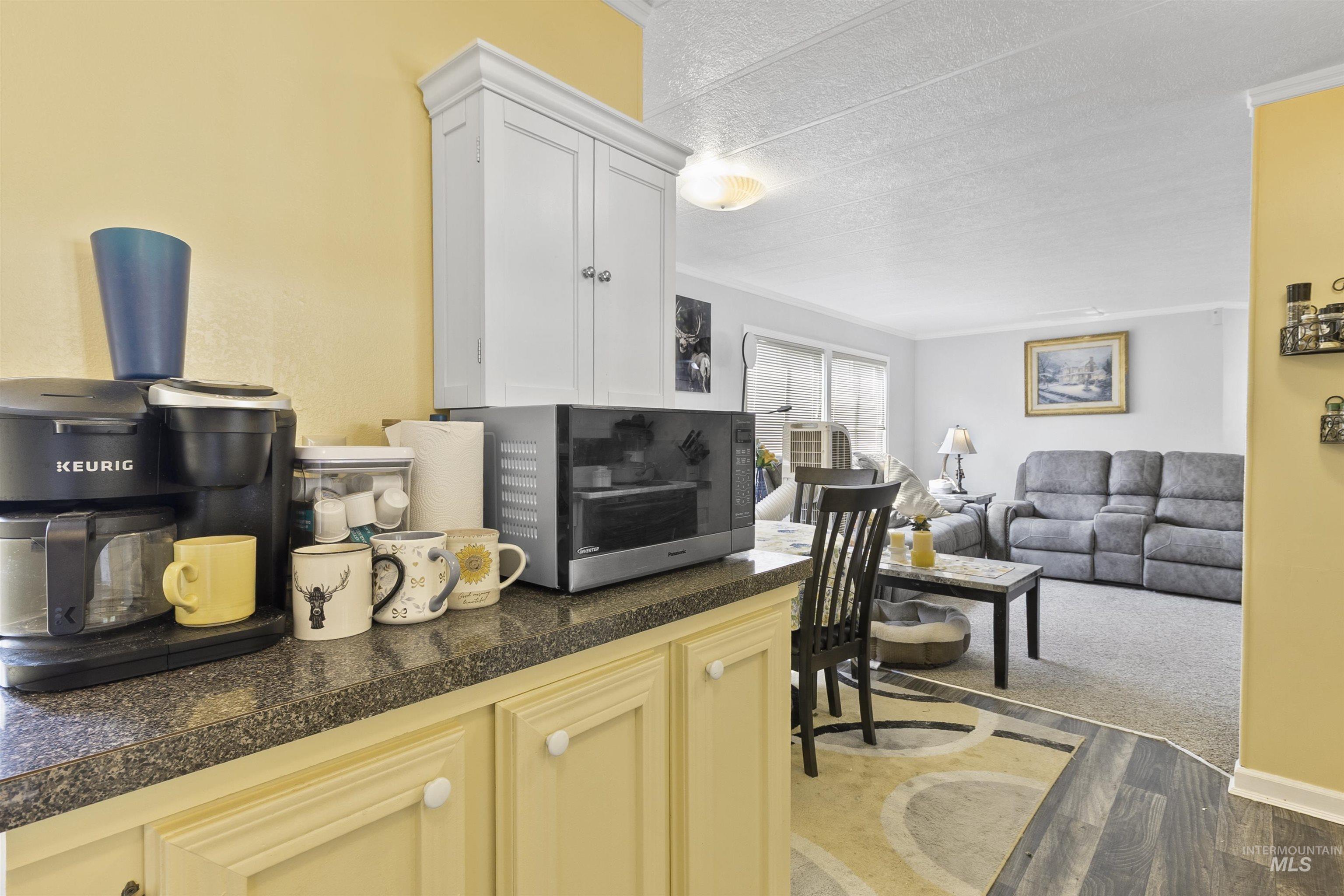 Kitchen featuring dark wood-style flooring, open floor plan, a textured ceiling, tile counters, and ornamental molding