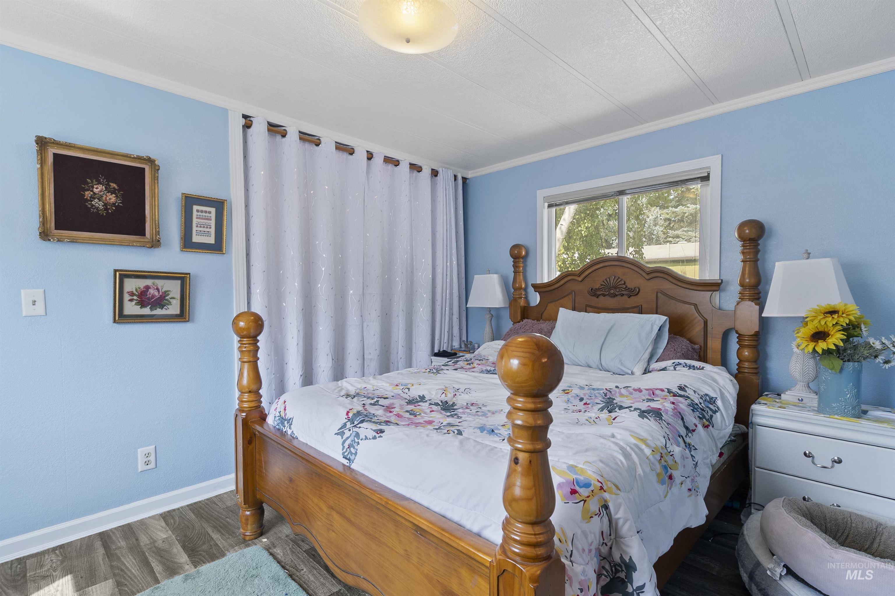 Bedroom with ornamental molding, wood finished floors, and a textured ceiling