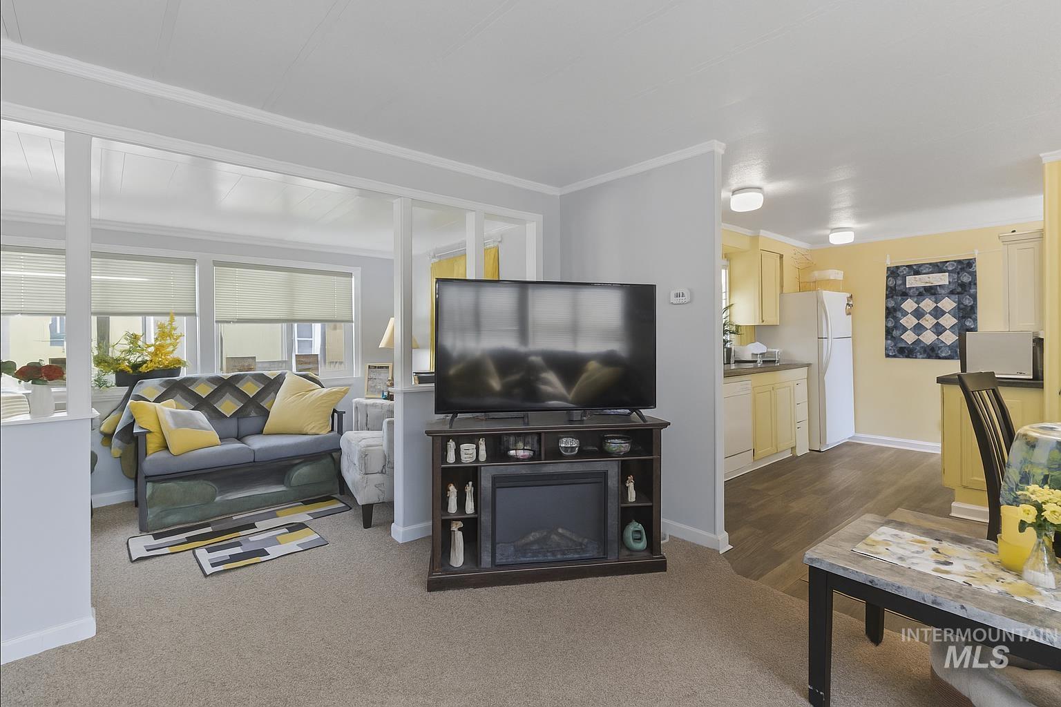 Living room featuring dark colored carpet and crown molding