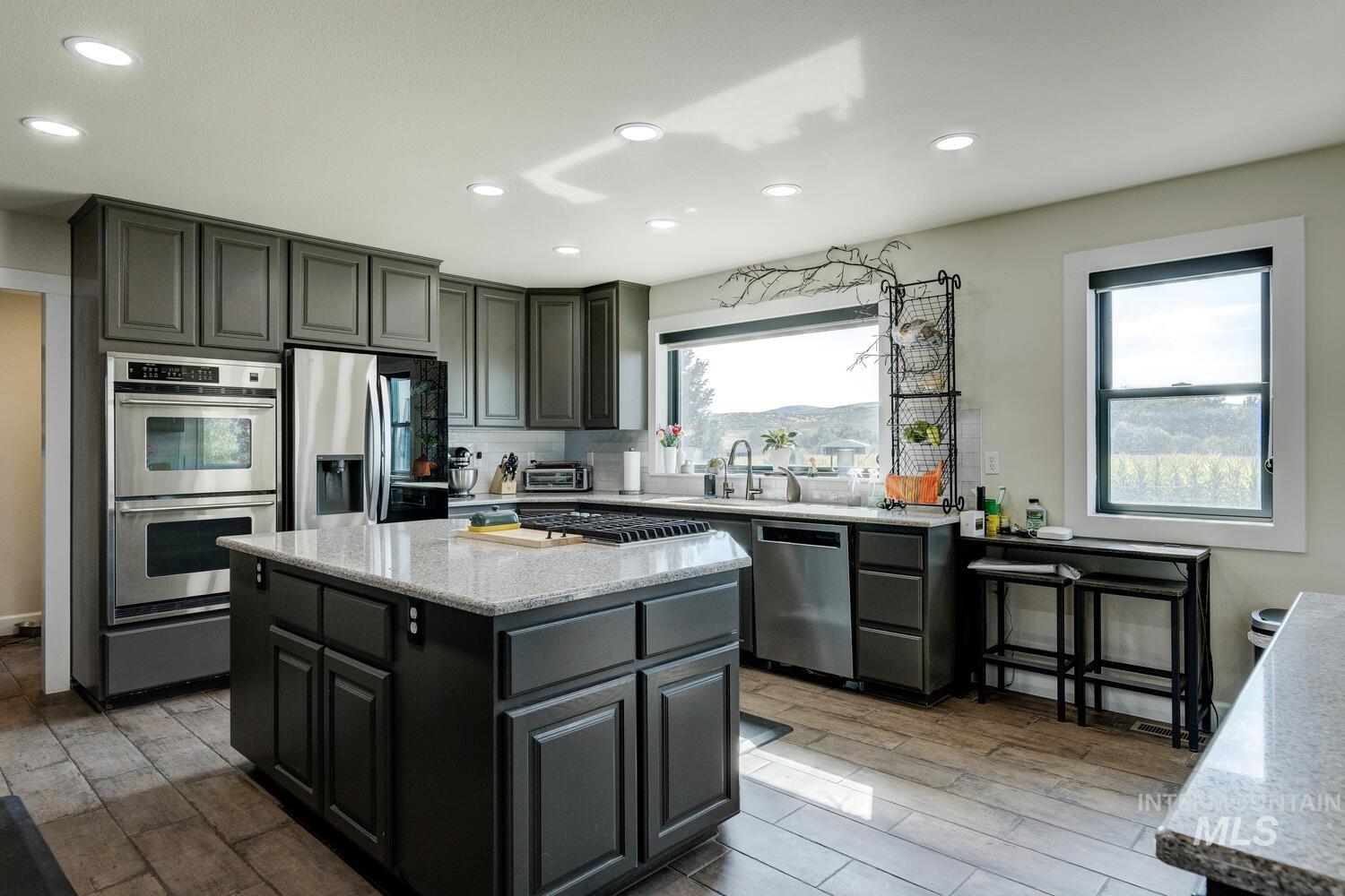 Kitchen with quartz counters, tiled floors, appliances with stainless steel finishes, recessed lighting, and a kitchen island