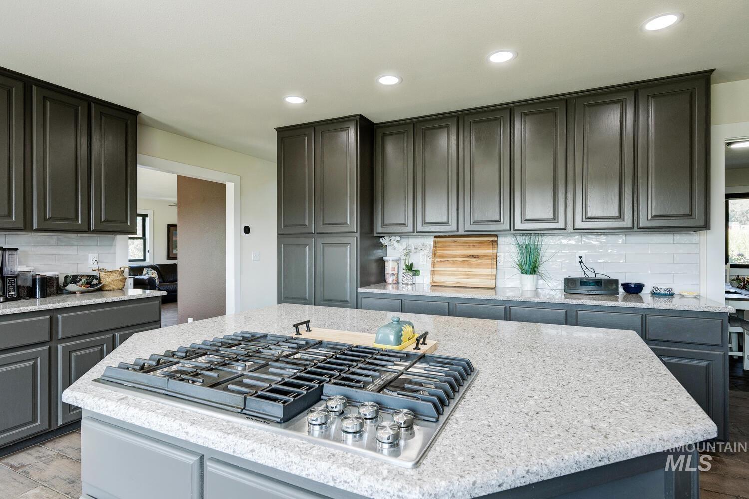 Kitchen featuring decorative backsplash, gray cabinetry, stainless steel gas cooktop, quartz countertops, and recessed lighting