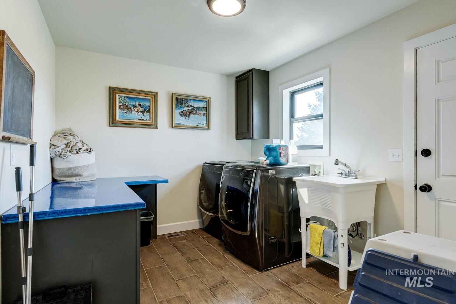 Laundry area with tile floors, utility sink, and cabinet space