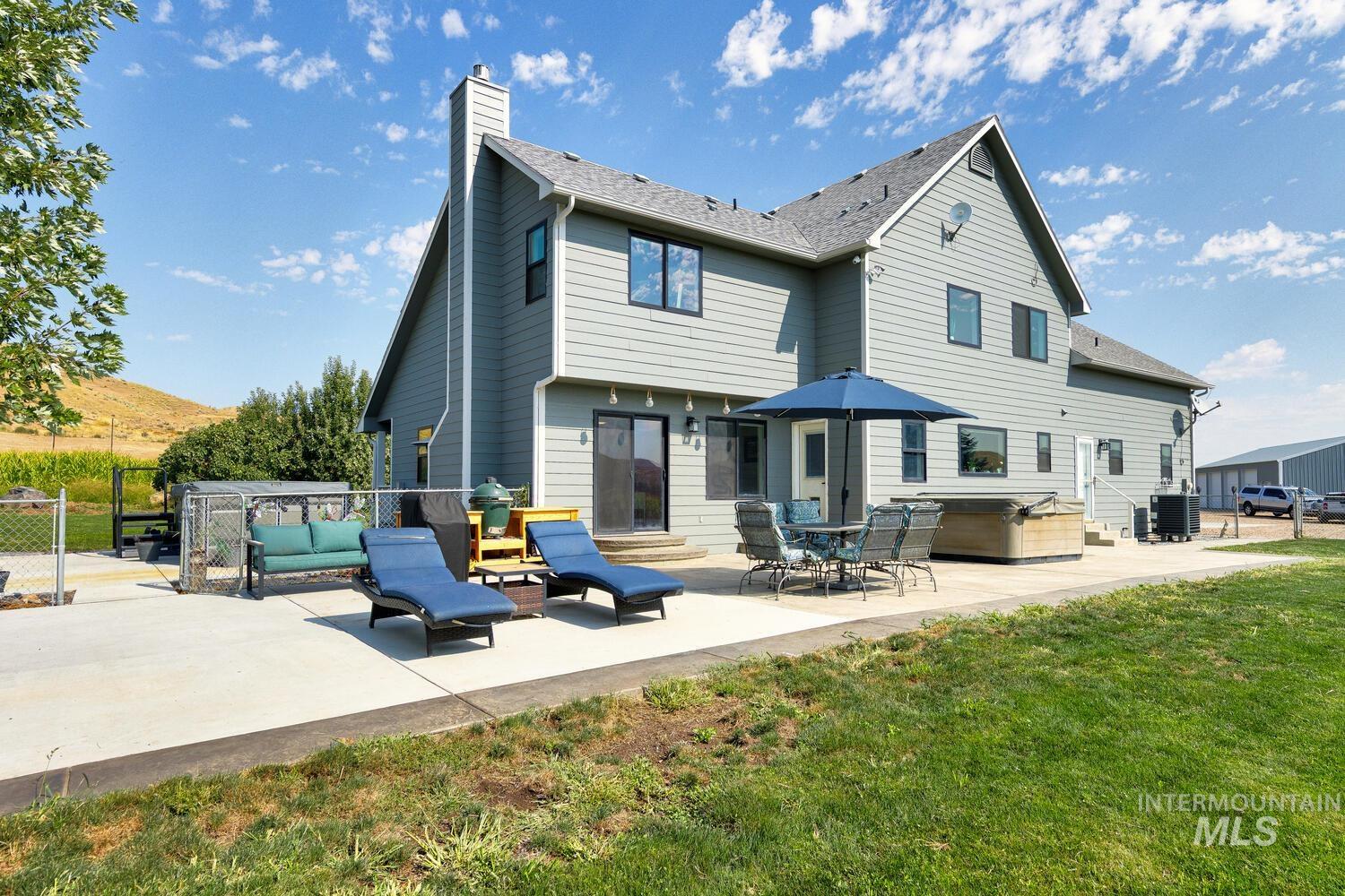 Back of house with a patio, an outdoor living space, a hot tub, and fenced yard