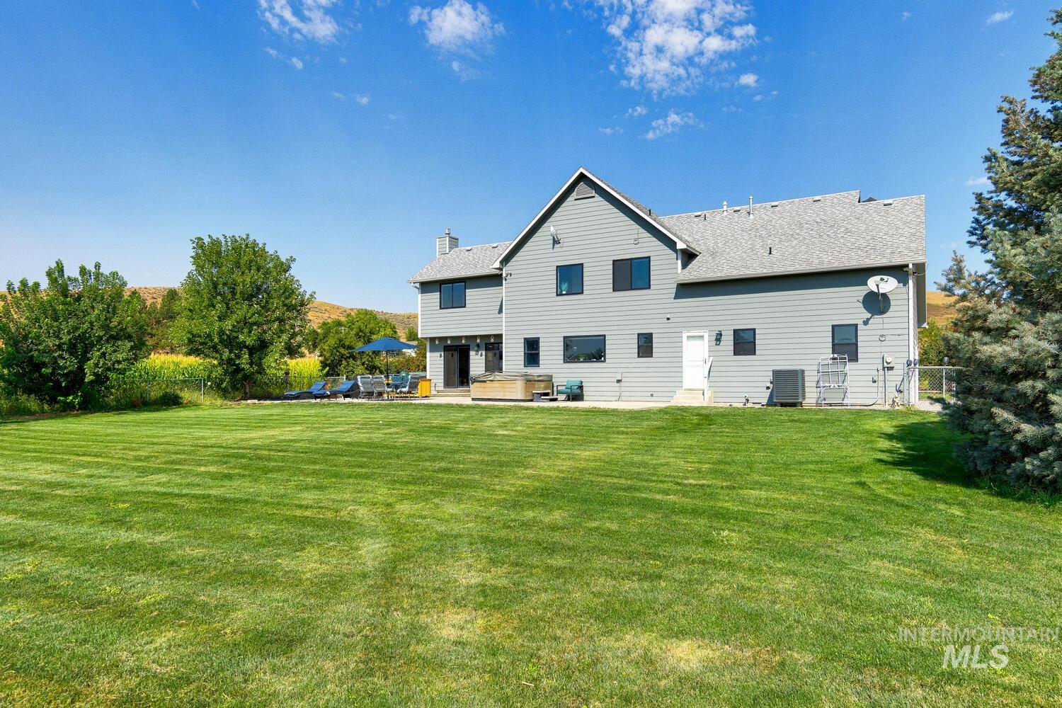 Back of house with a patio, an outdoor living space, a hot tub, and fenced yard