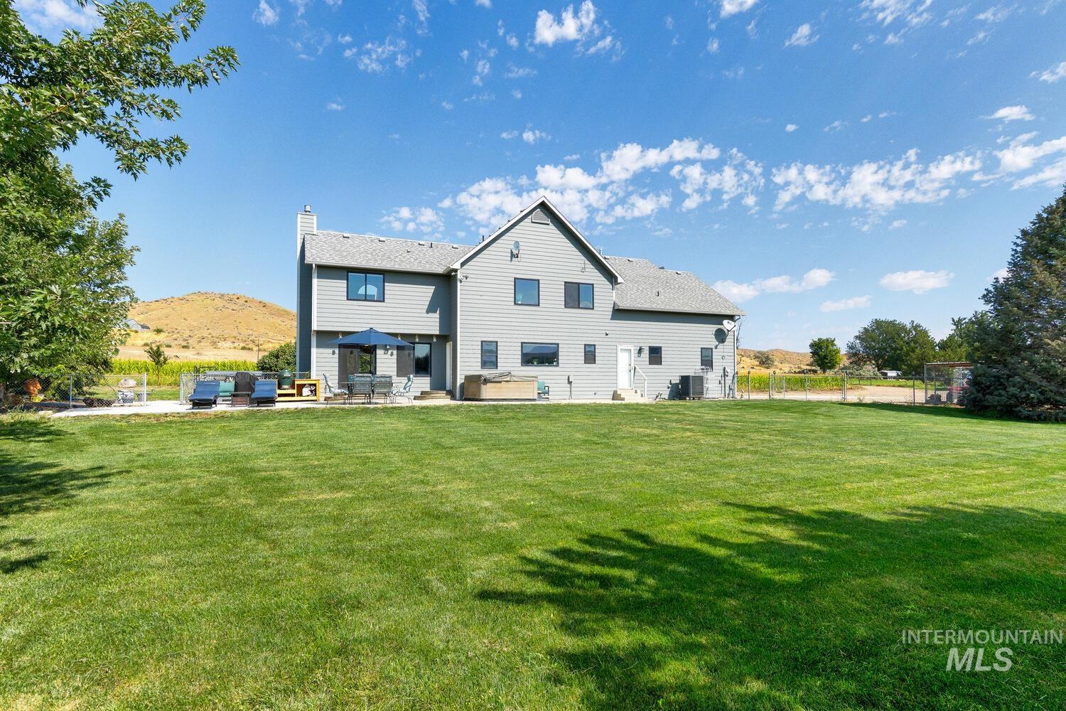Back of house with a patio, an outdoor living space, a hot tub, and fenced yard