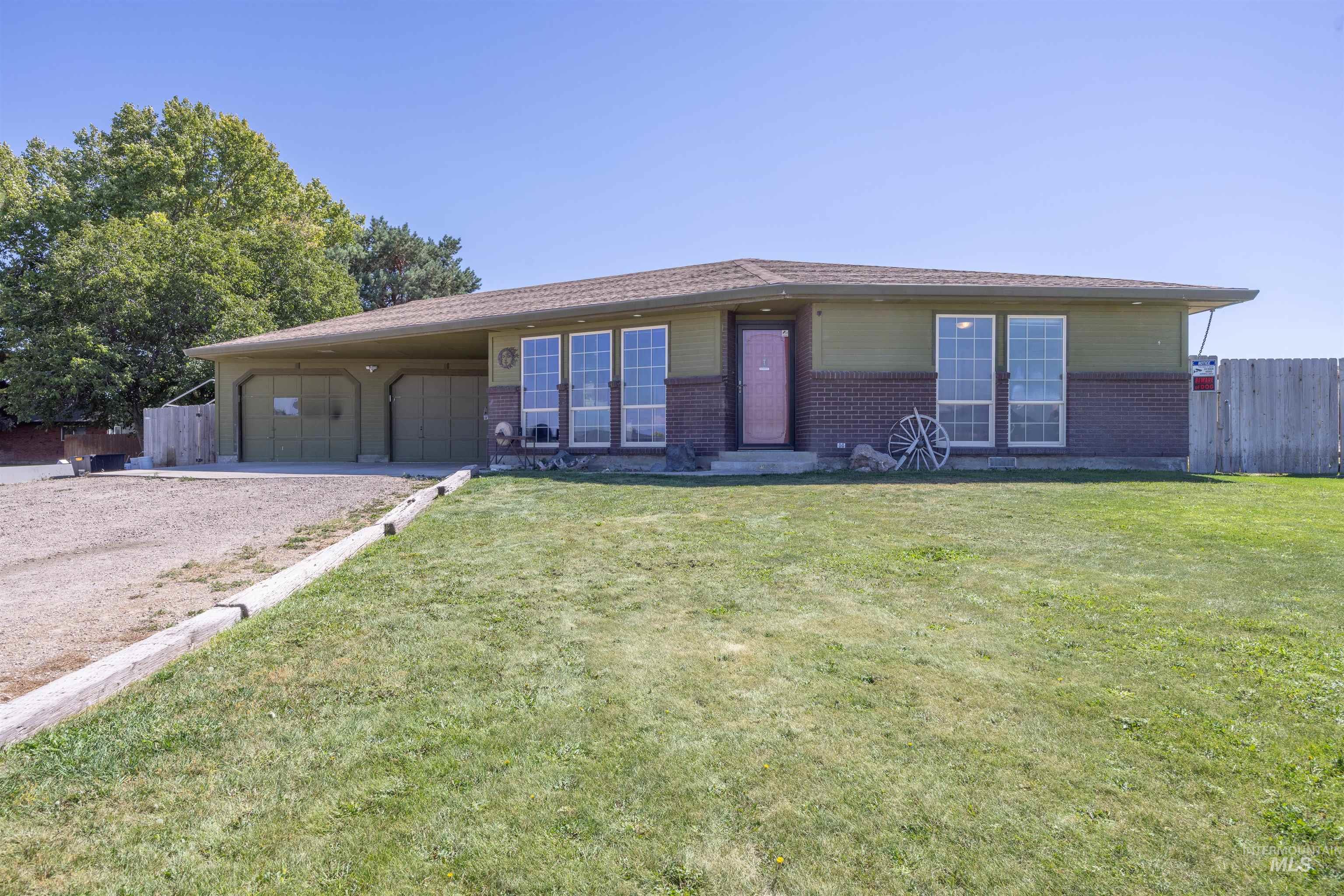 Single story home featuring driveway, brick siding, and a garage