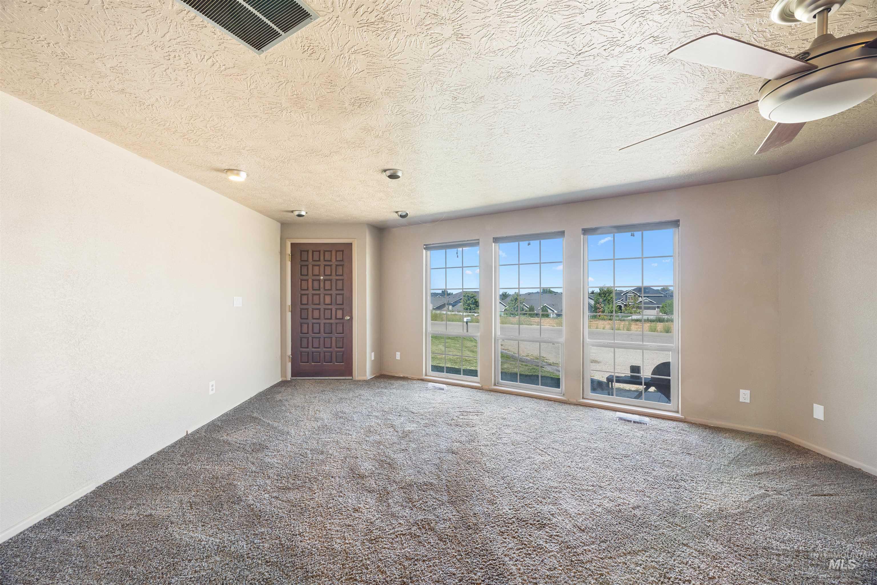 Carpeted spare room featuring a textured ceiling and ceiling fan