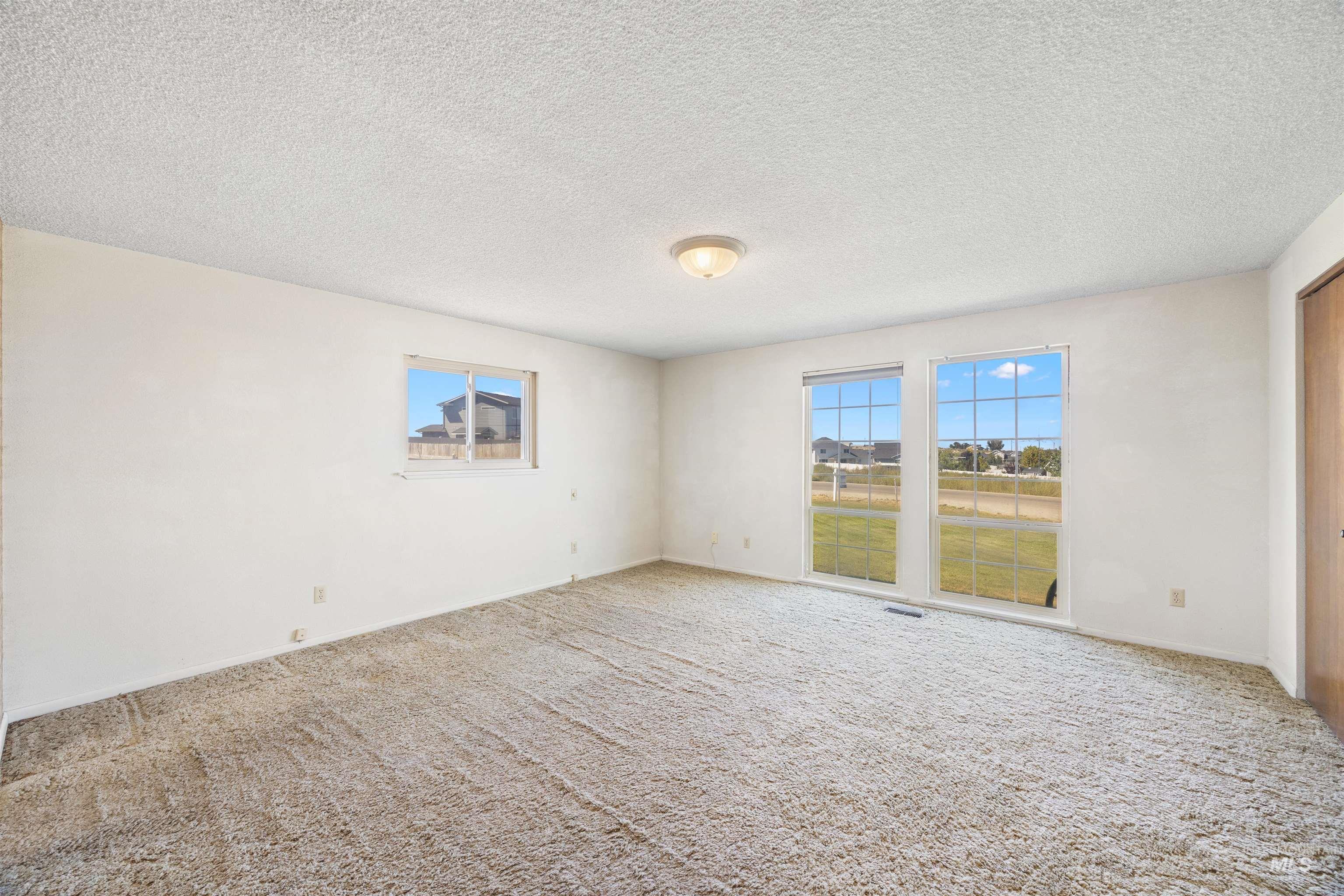 Unfurnished room with healthy amount of natural light, a textured ceiling, and carpet flooring