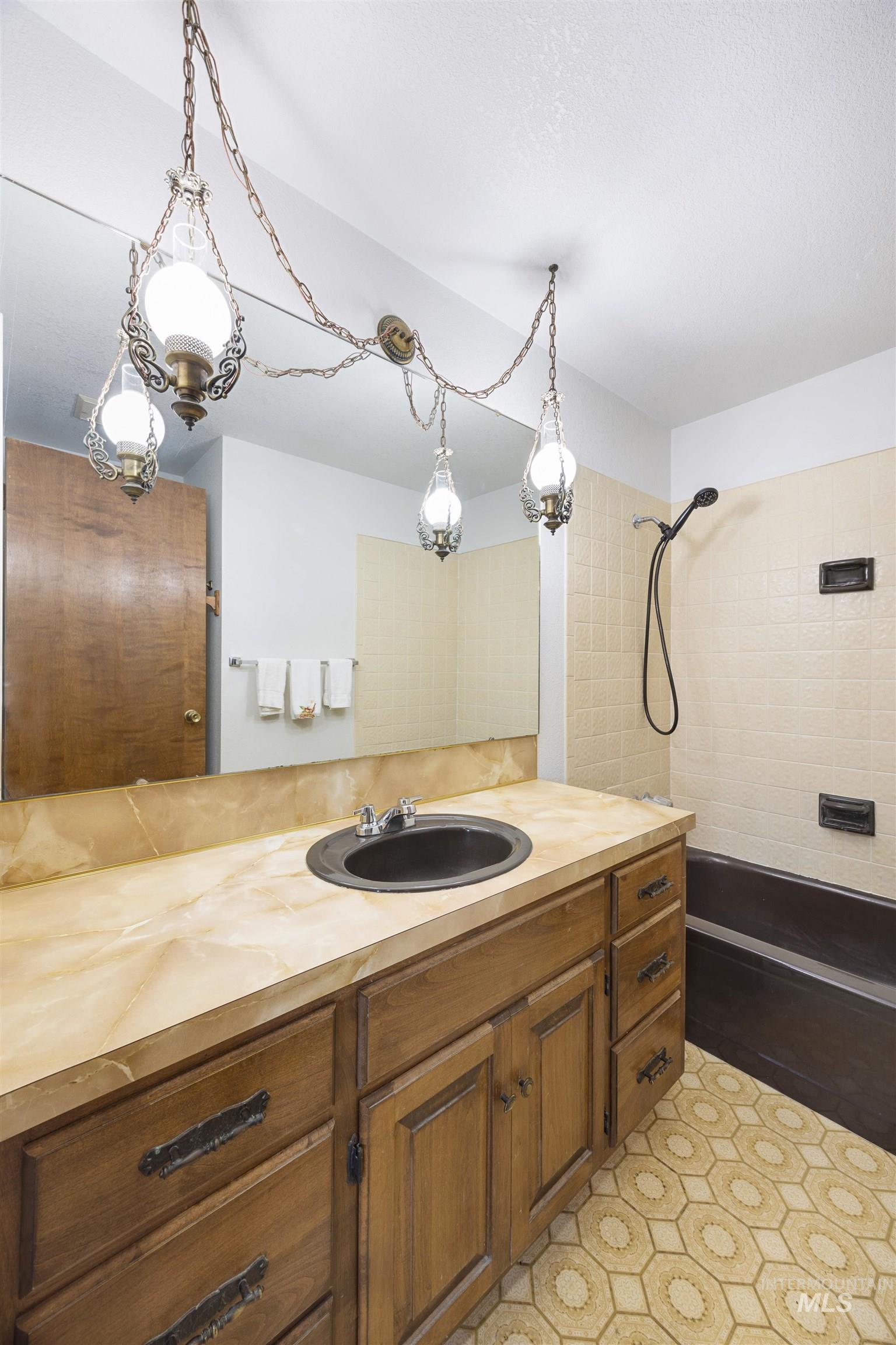 Bathroom featuring vanity, a tile shower, and light tile patterned flooring