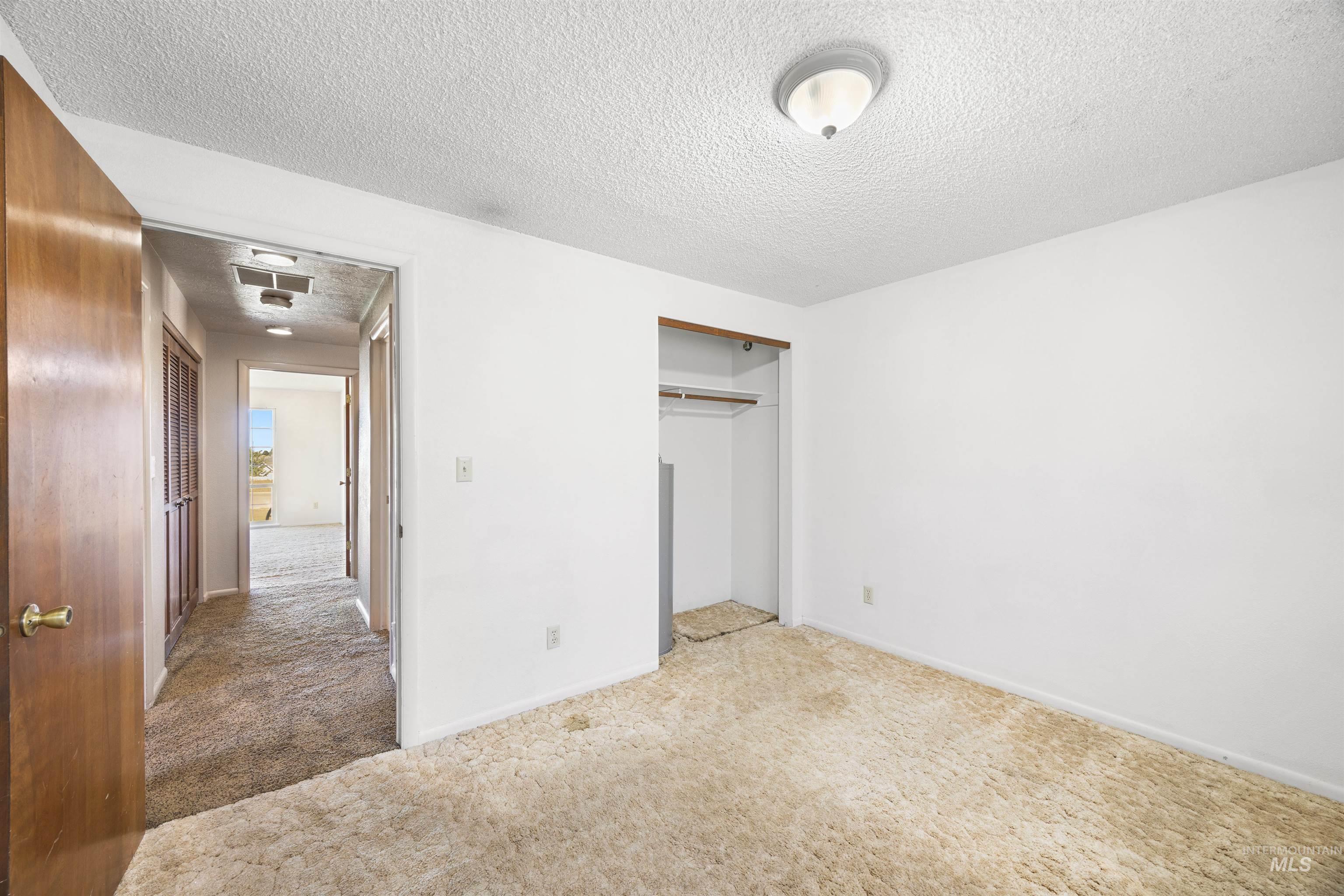 Unfurnished bedroom with carpet floors, a textured ceiling, and a closet