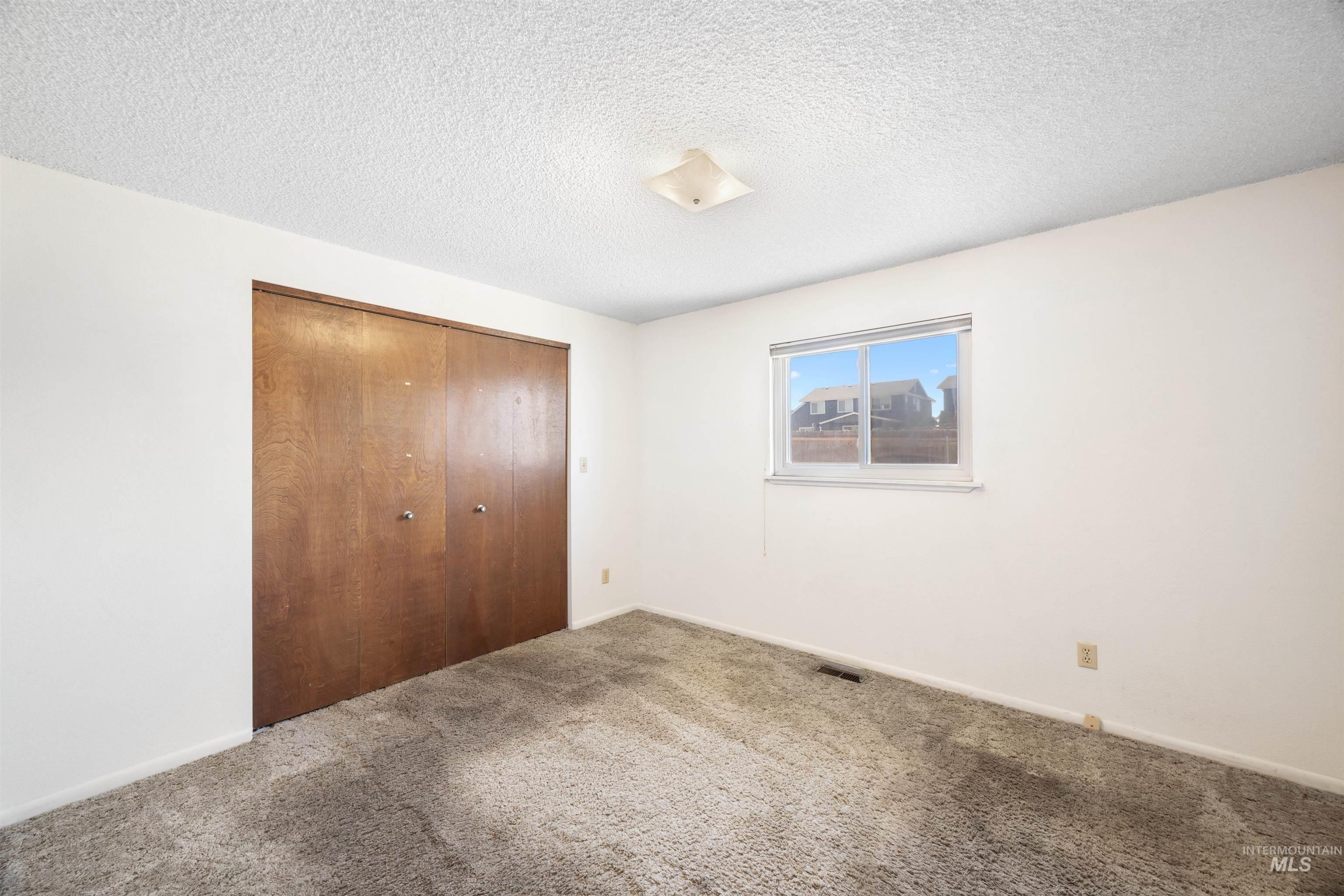 Unfurnished bedroom featuring a textured ceiling, a closet, and carpet floors