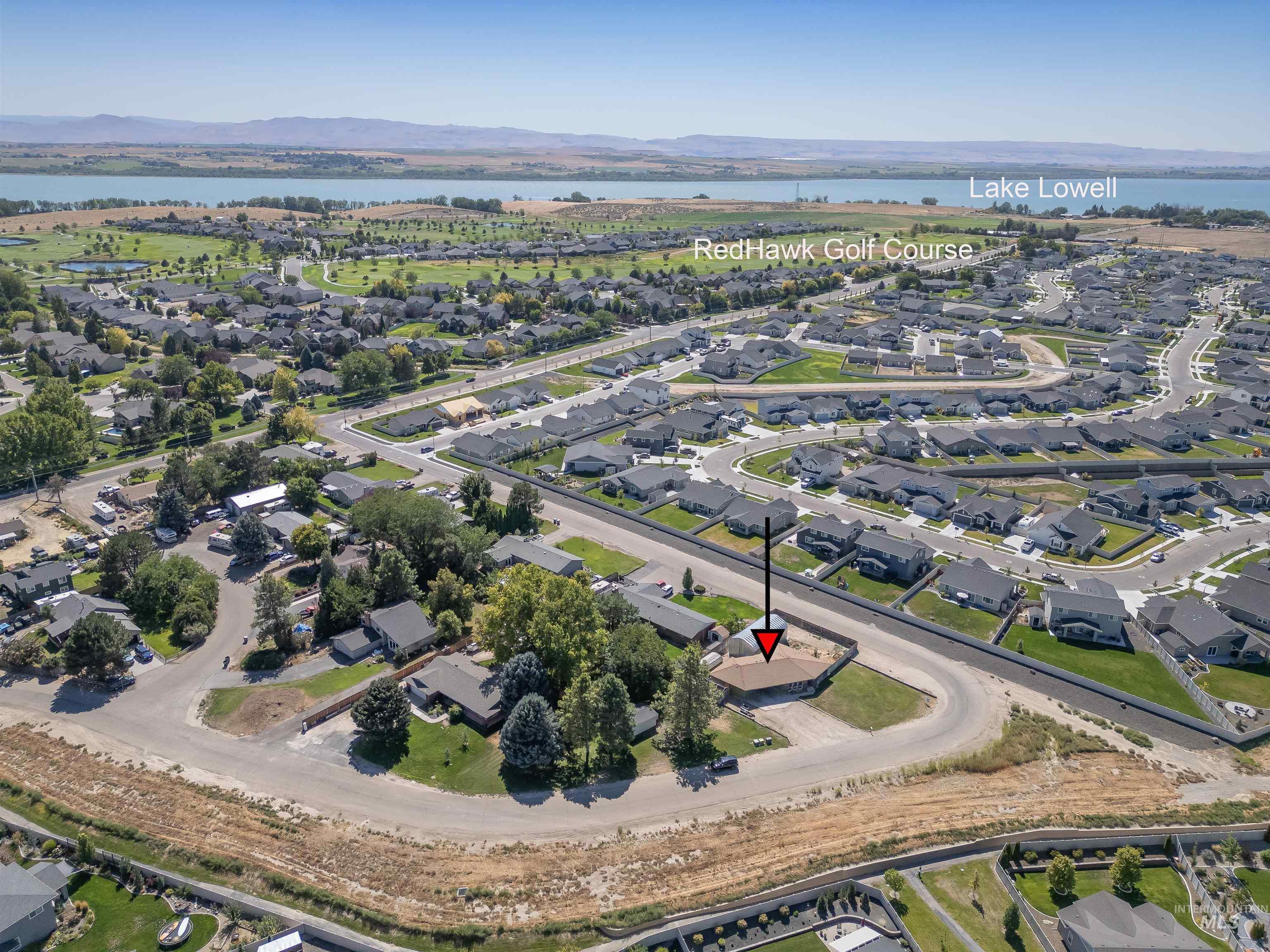 Aerial view of property and surrounding area featuring nearby suburban area and a water and mountain view