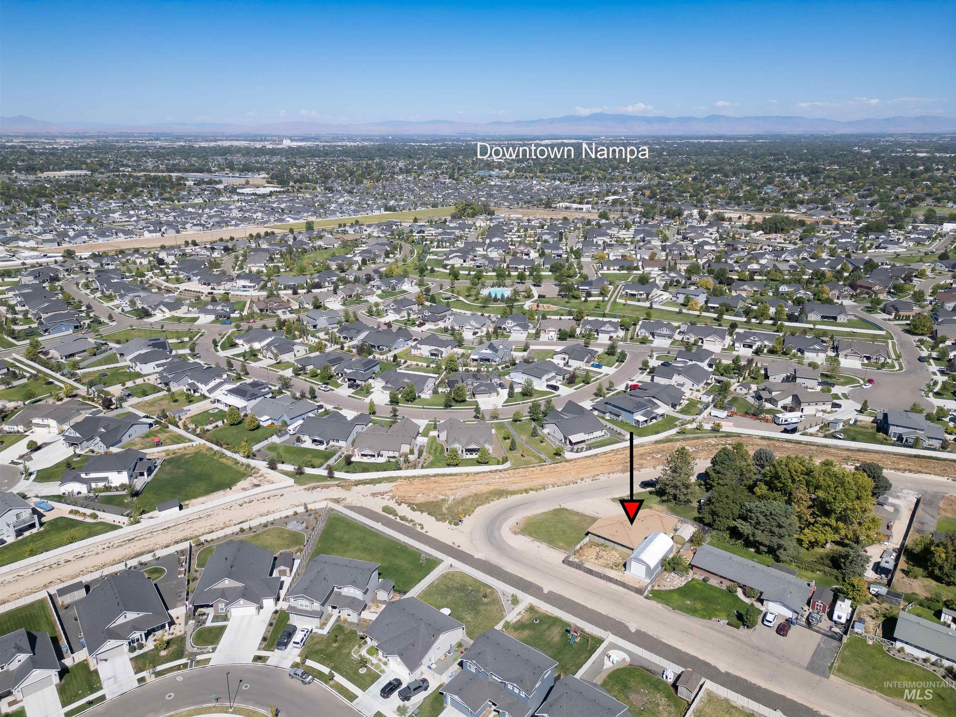 Aerial view of property and surrounding area with nearby suburban area and a mountain backdrop