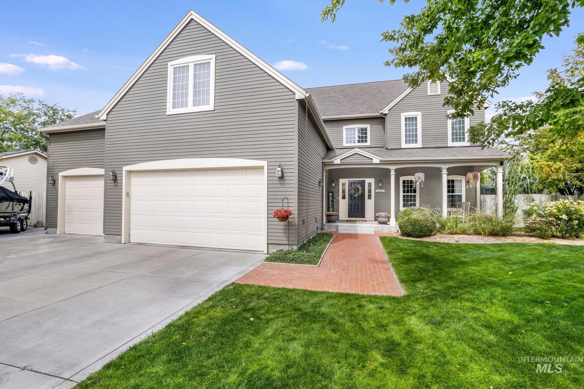 Traditional home featuring covered porch, a shingled roof, driveway, and an attached garage
