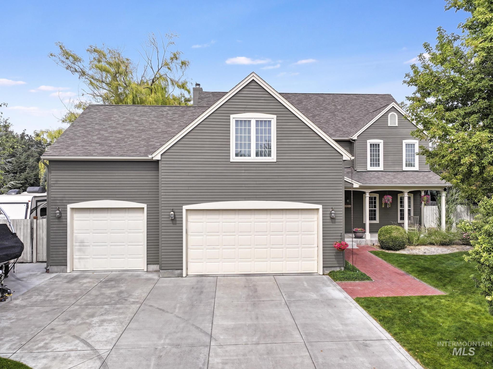 Traditional home featuring a porch, a shingled roof, driveway, and a chimney