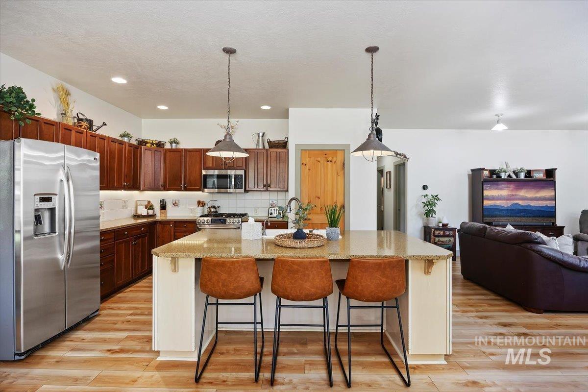 Kitchen featuring stainless steel appliances, a kitchen breakfast bar, decorative backsplash, pendant lighting, and recessed lighting