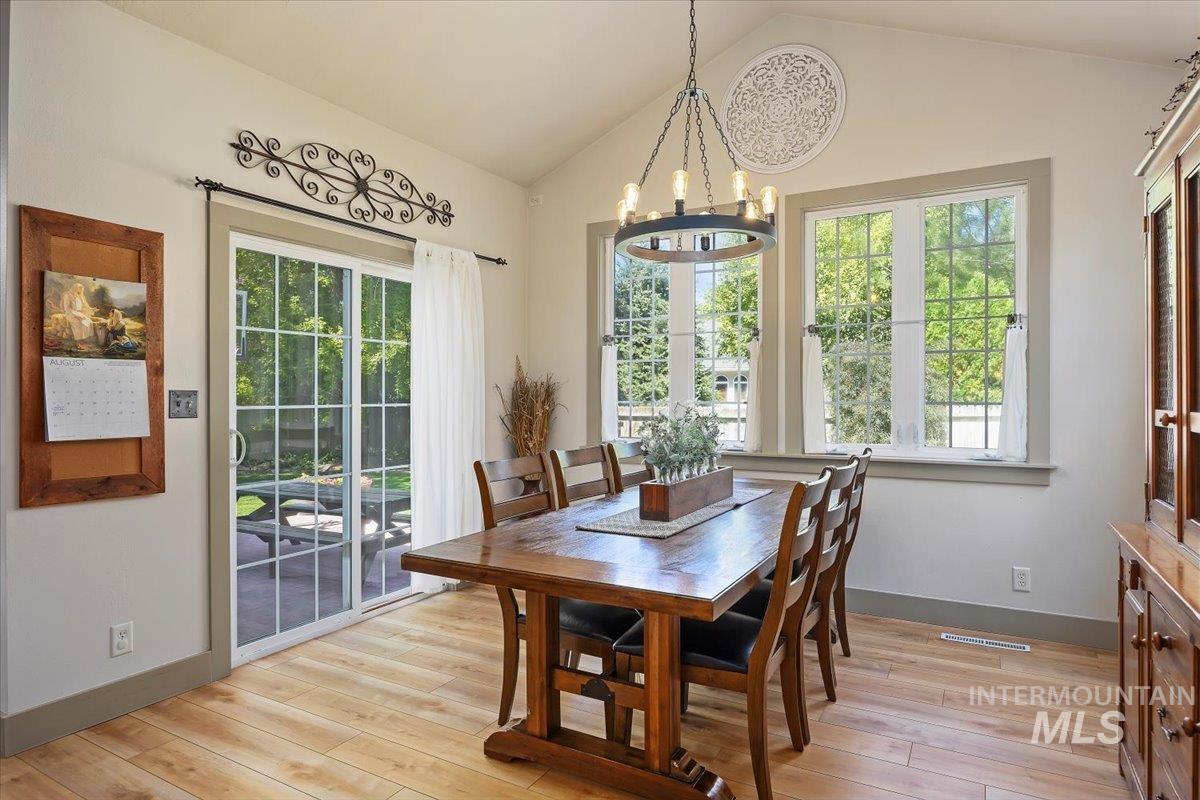 Dining room with vaulted ceiling, light wood-type flooring, and a chandelier
