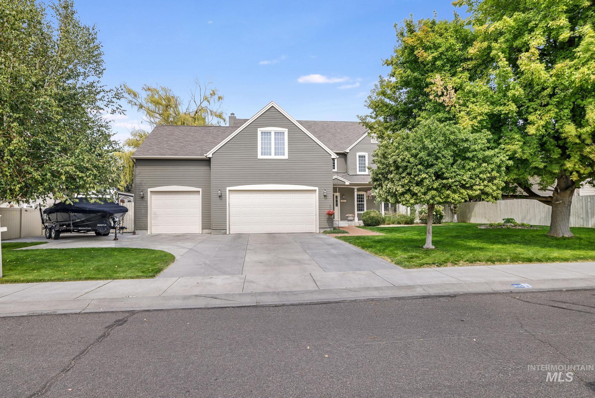 Traditional home with driveway, a shingled roof, an attached garage, covered porch, and a chimney