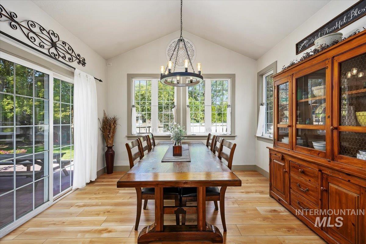 Dining area featuring vaulted ceiling, a chandelier, and light wood-style floors