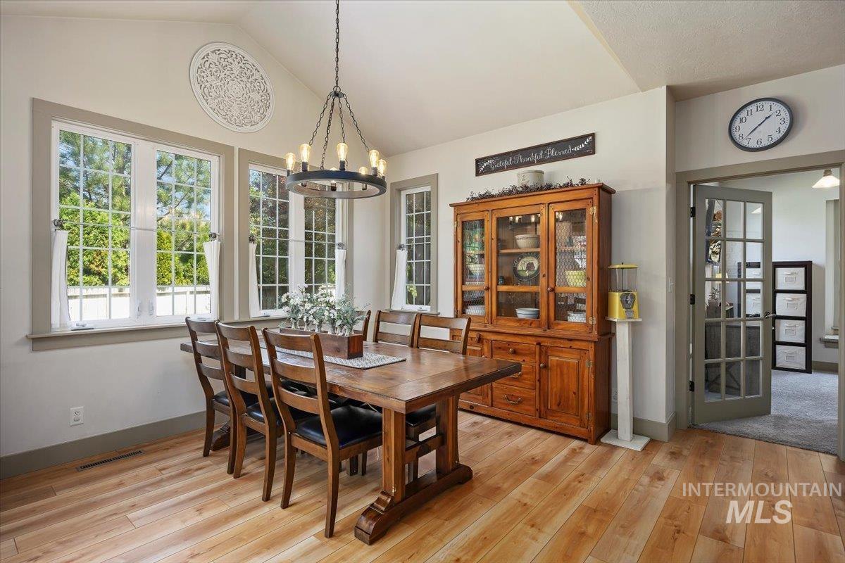 Dining space featuring vaulted ceiling, a chandelier, and light wood-style floors