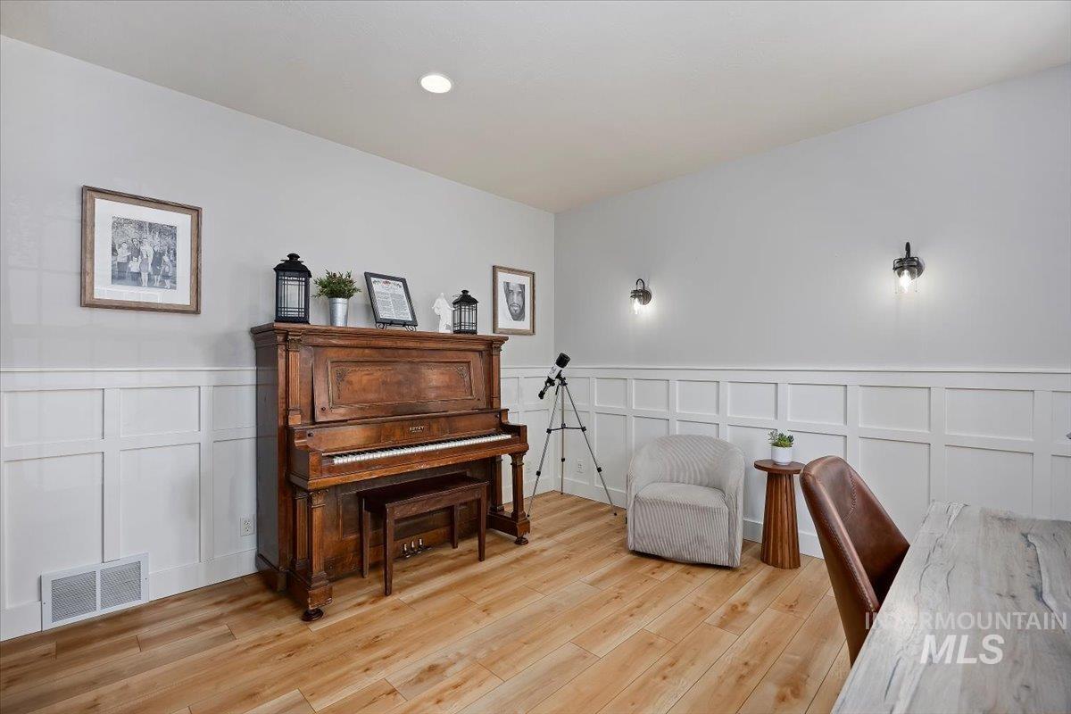 Living area with a decorative wall, wainscoting, and light wood finished floors