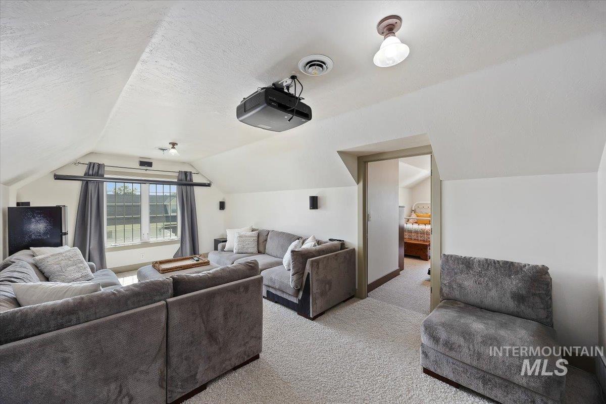 Home theater room featuring lofted ceiling, a textured ceiling, and carpet flooring